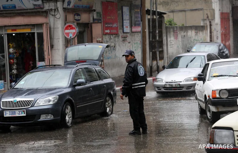 Palestinians walk in a flooded street during a rainy day, in Gaza City on April 12, 2016. Photo by Mohammed Asad