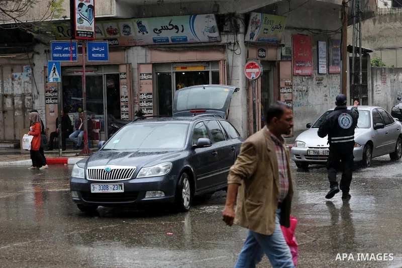 Palestinians walk in a flooded street during a rainy day, in Gaza City on April 12, 2016. Photo by Mohammed Asad