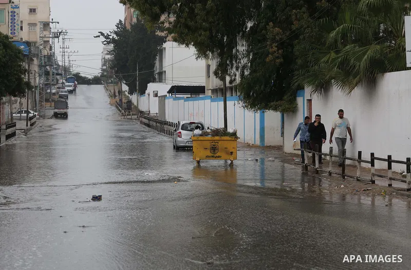 Palestinians walk in a flooded street during a rainy day, in Gaza City on April 12, 2016. Photo by Mohammed Asad