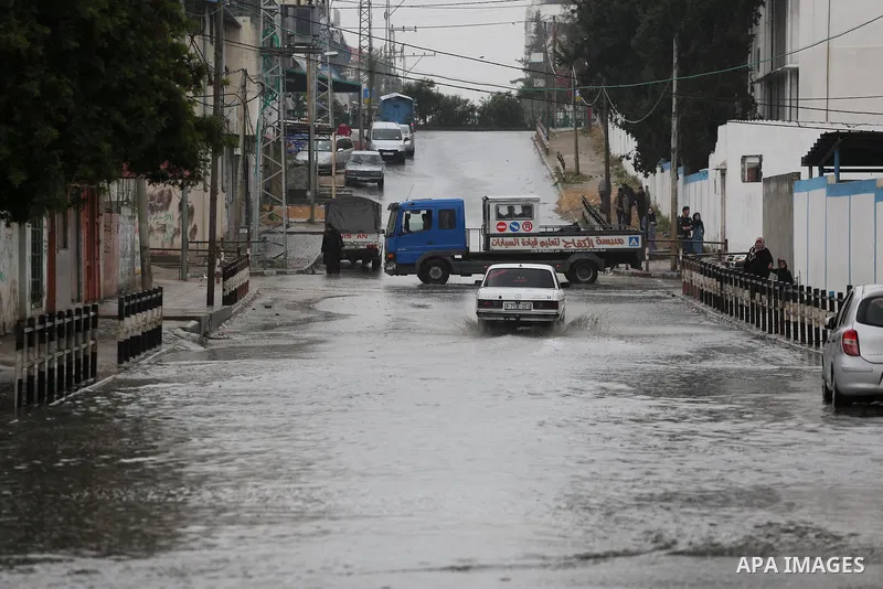 Palestinians walk in a flooded street during a rainy day, in Gaza City on April 12, 2016. Photo by Mohammed Asad