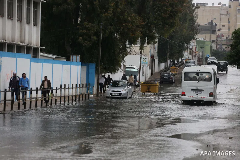 Palestinians walk in a flooded street during a rainy day, in Gaza City on April 12, 2016. Photo by Mohammed Asad