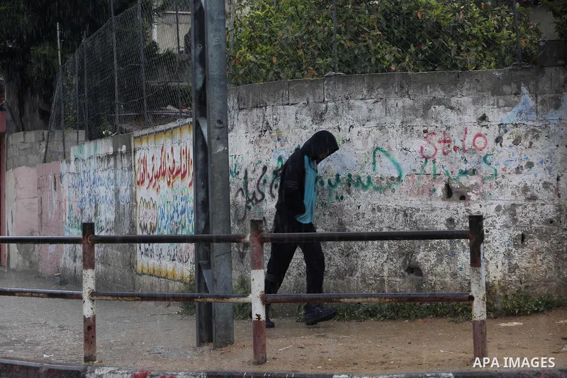 Palestinians walk in a flooded street during a rainy day, in Gaza City on April 12, 2016. Photo by Mohammed Asad