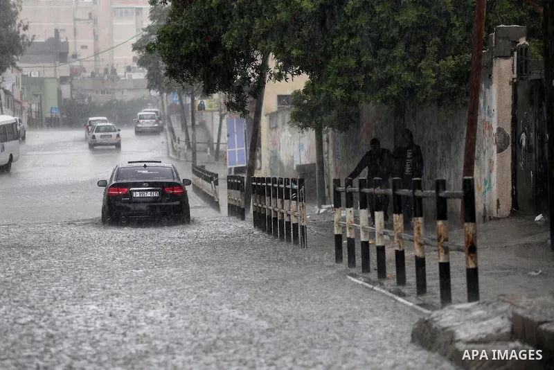 Palestinians walk in a flooded street during a rainy day, in Gaza City on April 12, 2016. Photo by Mohammed Asad
