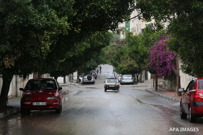 Palestinians walk in a flooded street during a rainy day, in Gaza City on April 12, 2016. Photo by Mohammed Asad