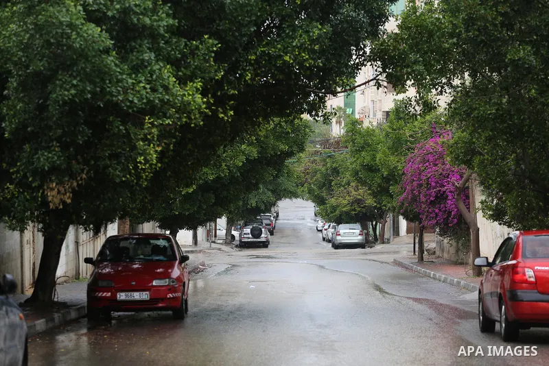 Palestinians walk in a flooded street during a rainy day, in Gaza City on April 12, 2016. Photo by Mohammed Asad