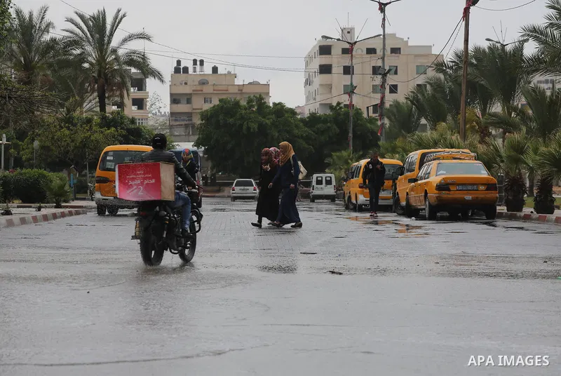 Palestinians walk in a flooded street during a rainy day, in Gaza City on April 12, 2016. Photo by Mohammed Asad