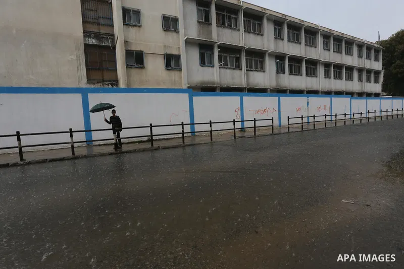 Palestinians walk in a flooded street during a rainy day, in Gaza City on April 12, 2016. Photo by Mohammed Asad