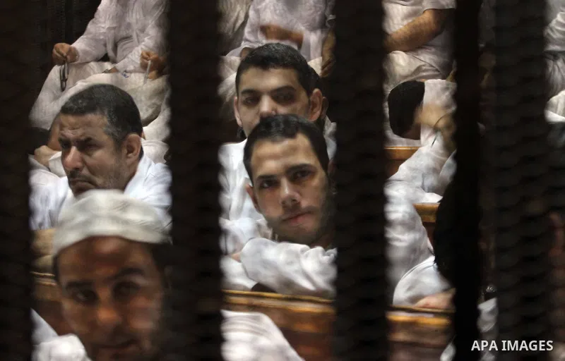 Muslim Brotherhood members sit behind the defendants cage as they attend their trial along with Egyptian Muslim Brotherhood leader Mohammed Badie (unseen), at a court in the outskirts of Cairo, Egypt, on April 12, 2016....