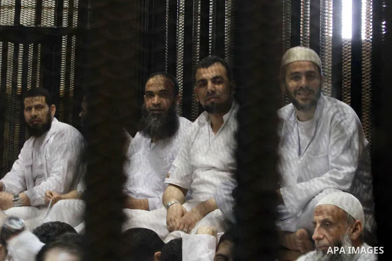 Muslim Brotherhood members sit behind the defendants cage as they attend their trial along with Egyptian Muslim Brotherhood leader Mohammed Badie (unseen), at a court in the outskirts of Cairo, Egypt, on April 12, 2016....