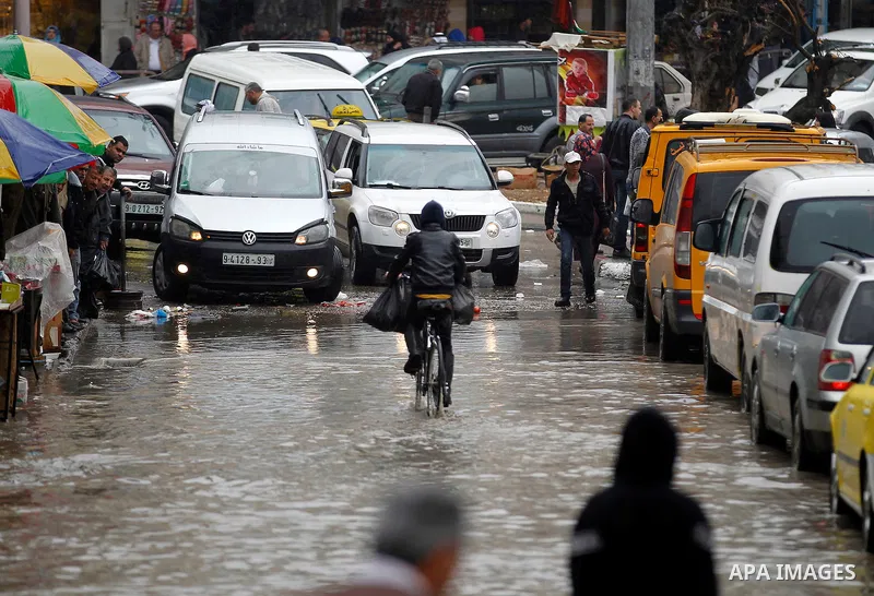 Palestinians walk in a flooded street during a rainy day, in the West Bank city of Hebron on April 12, 2016. Photo by Wisam Hashlamoun