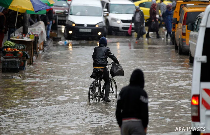Palestinians walk in a flooded street during a rainy day, in the West Bank city of Hebron on April 12, 2016. Photo by Wisam Hashlamoun