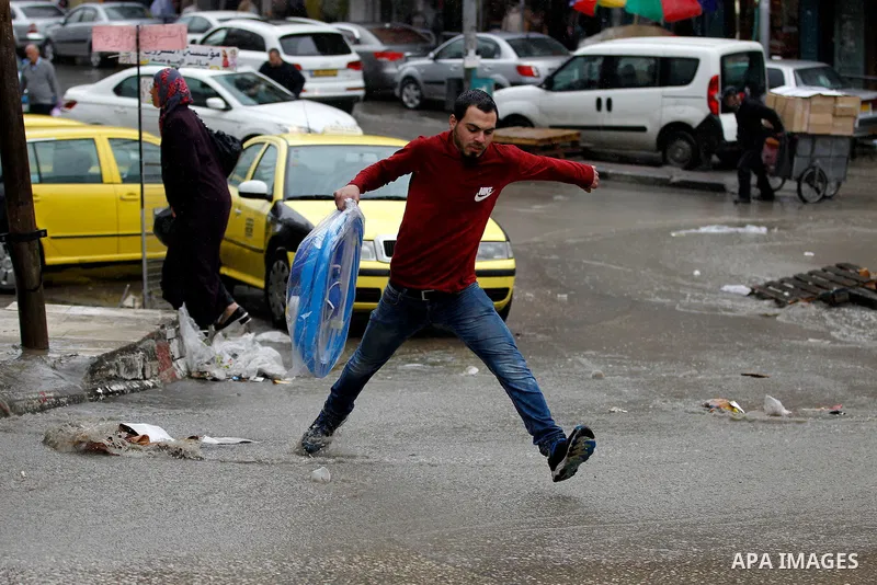 Palestinians walk in a flooded street during a rainy day, in the West Bank city of Hebron on April 12, 2016. Photo by Wisam Hashlamoun