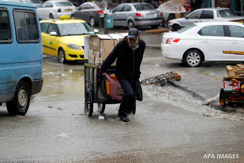 Palestinians walk in a flooded street during a rainy day, in the West Bank city of Hebron on April 12, 2016. Photo by Wisam Hashlamoun