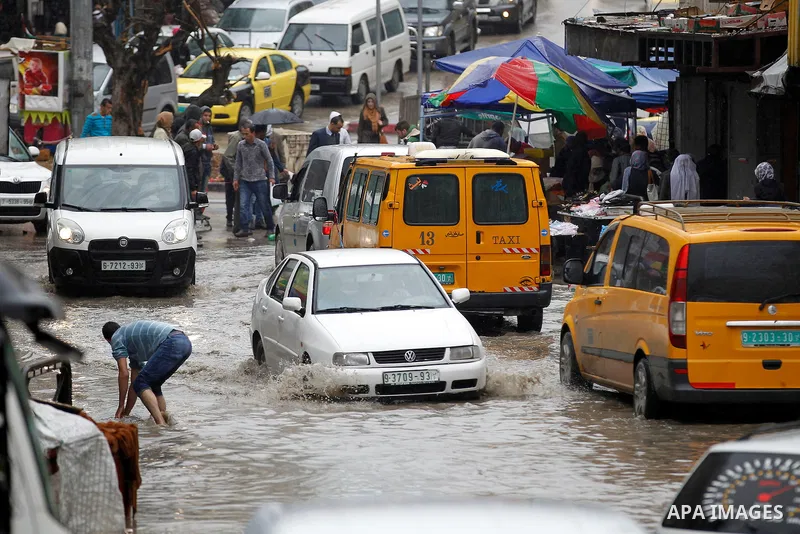 Palestinians walk in a flooded street during a rainy day, in the West Bank city of Hebron on April 12, 2016. Photo by Wisam Hashlamoun