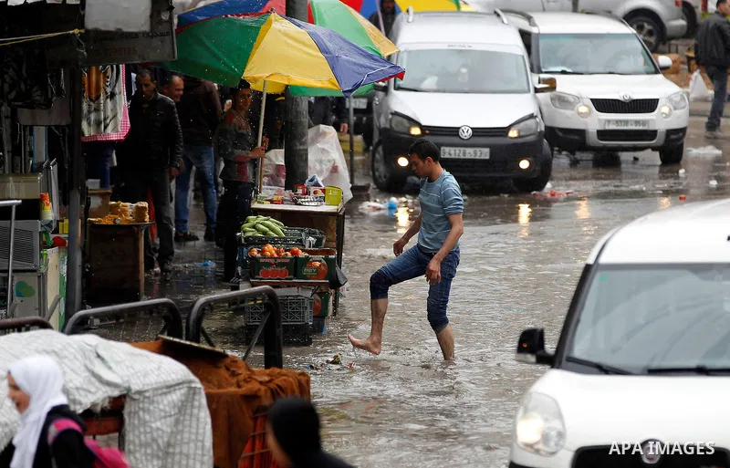Palestinians walk in a flooded street during a rainy day, in the West Bank city of Hebron on April 12, 2016. Photo by Wisam Hashlamoun