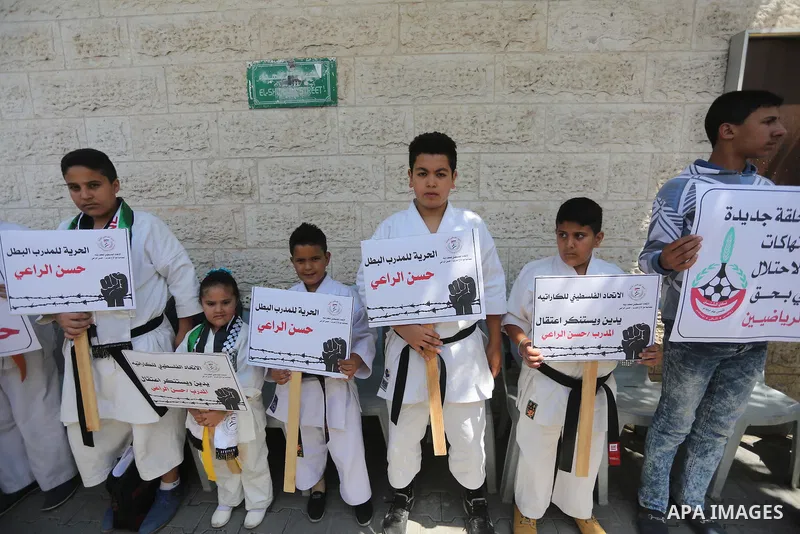 Palestinians hold banners during a protest in solidarity with the karate trainer, Hassan El-Raey against his arrest by the Israeli army, in front of Red cross office in Gaza city on April 13, 2016. Photo by Mohammed Asad