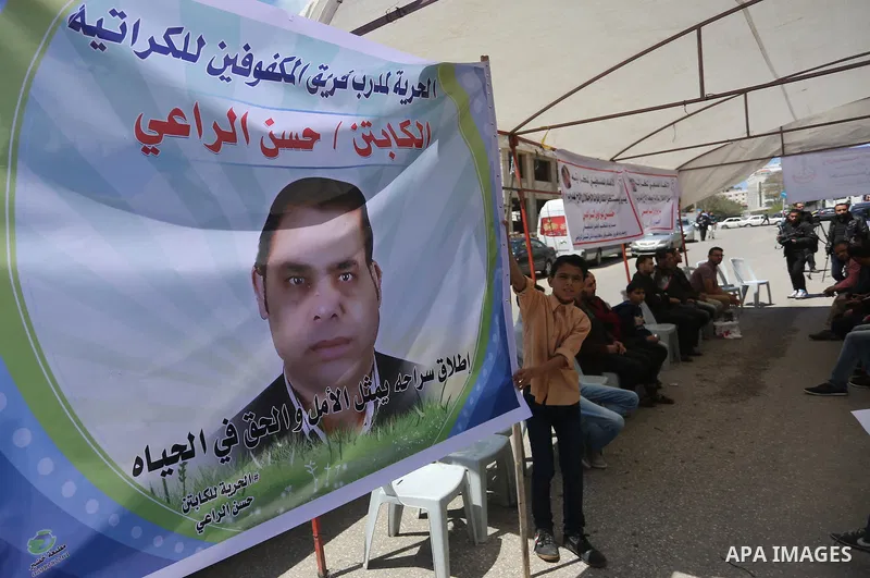 Palestinians hold banners during a protest in solidarity with the karate trainer, Hassan El-Raey against his arrest by the Israeli army, in front of Red cross office in Gaza city on April 13, 2016. Photo by Mohammed Asad