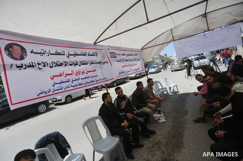 Palestinians hold banners during a protest in solidarity with the karate trainer, Hassan El-Raey against his arrest by the Israeli army, in front of Red cross office in Gaza city on April 13, 2016. Photo by Mohammed Asad