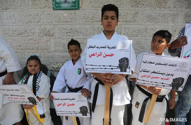 Palestinians hold banners during a protest in solidarity with the karate trainer, Hassan El-Raey against his arrest by the Israeli army, in front of Red cross office in Gaza city on April 13, 2016. Photo by Mohammed Asad