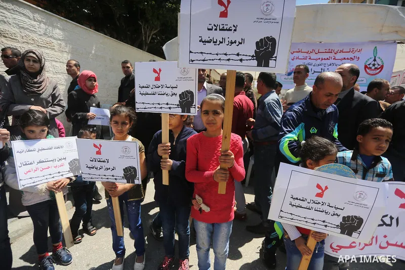 Palestinians hold banners during a protest in solidarity with the karate trainer, Hassan El-Raey against his arrest by the Israeli army, in front of Red cross office in Gaza city on April 13, 2016. Photo by Mohammed Asad