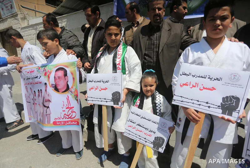 Palestinians hold banners during a protest in solidarity with the karate trainer, Hassan El-Raey against his arrest by the Israeli army, in front of Red cross office in Gaza city on April 13, 2016. Photo by Mohammed Asad