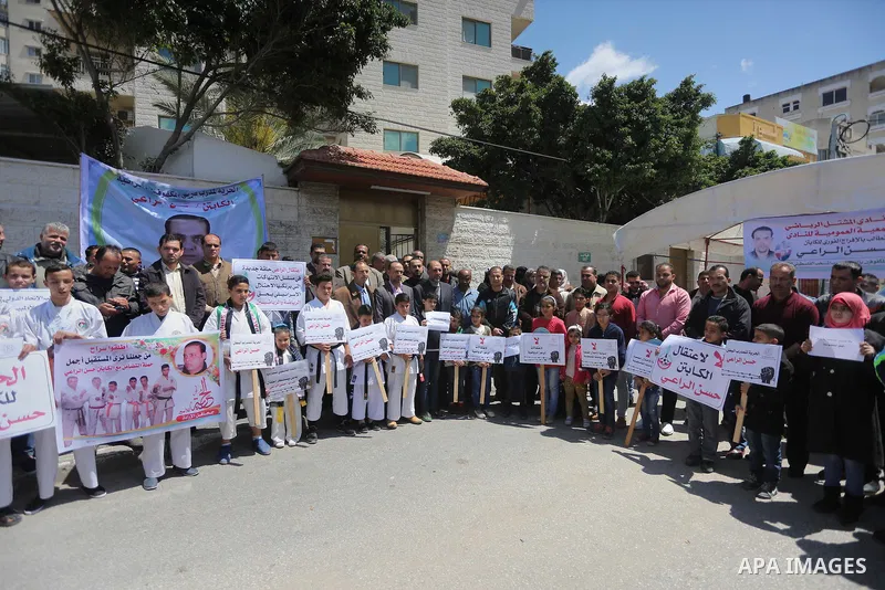Palestinians hold banners during a protest in solidarity with the karate trainer, Hassan El-Raey against his arrest by the Israeli army, in front of Red cross office in Gaza city on April 13, 2016. Photo by Mohammed Asad