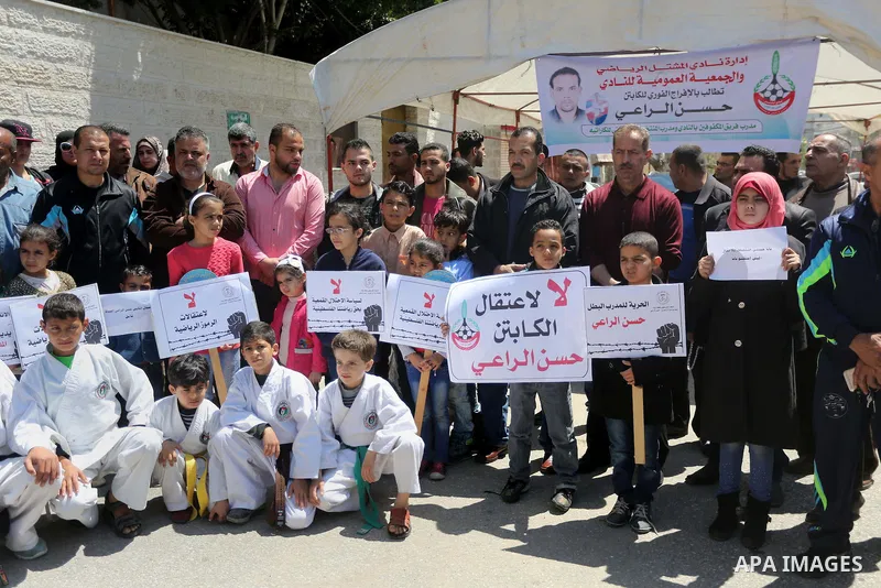 Palestinians hold banners during a protest in solidarity with the karate trainer, Hassan El-Raey against his arrest by the Israeli army, in front of Red cross office in Gaza city on April 13, 2016. Photo by Mohammed Asad