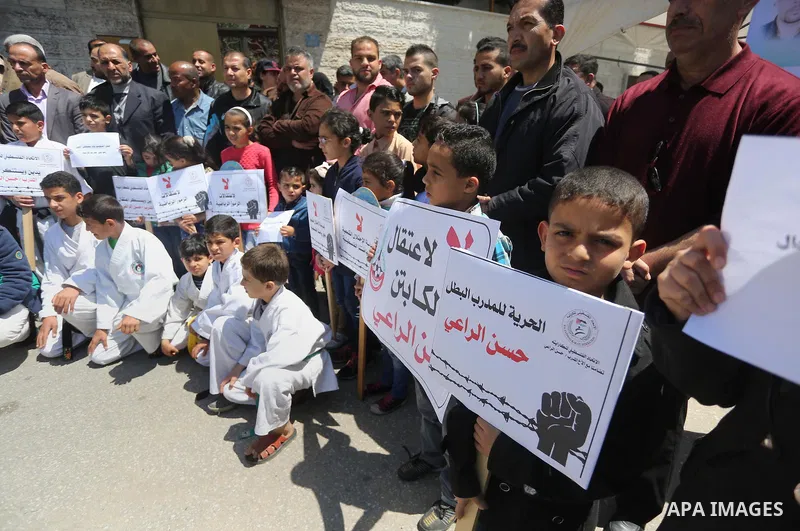 Palestinians hold banners during a protest in solidarity with the karate trainer, Hassan El-Raey against his arrest by the Israeli army, in front of Red cross office in Gaza city on April 13, 2016. Photo by Mohammed Asad