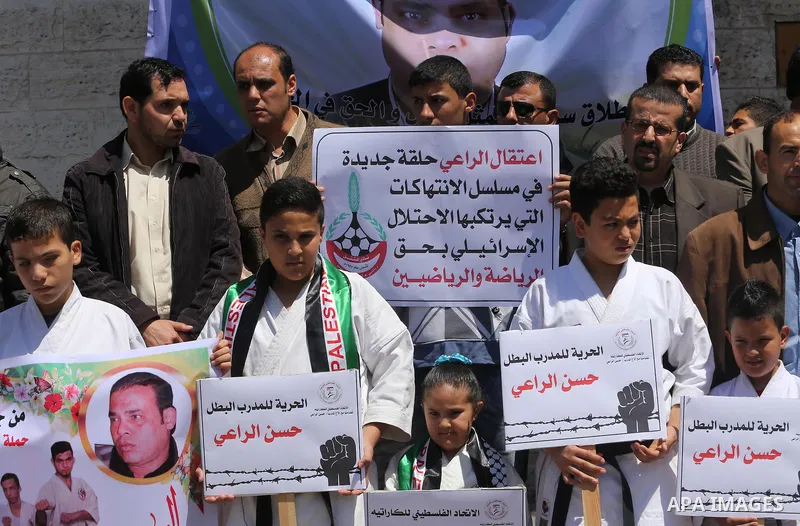 Palestinians hold banners during a protest in solidarity with the karate trainer, Hassan El-Raey against his arrest by the Israeli army, in front of Red cross office in Gaza city on April 13, 2016. Photo by Mohammed Asad