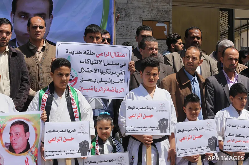 Palestinians hold banners during a protest in solidarity with the karate trainer, Hassan El-Raey against his arrest by the Israeli army, in front of Red cross office in Gaza city on April 13, 2016. Photo by Mohammed Asad