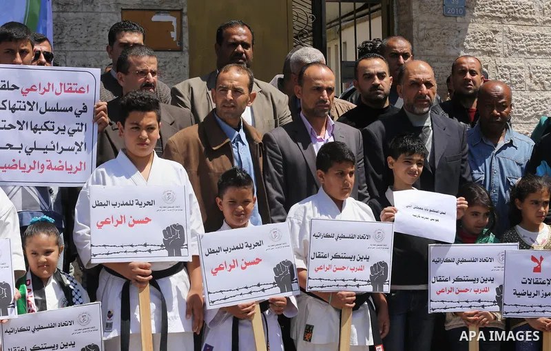 Palestinians hold banners during a protest in solidarity with the karate trainer, Hassan El-Raey against his arrest by the Israeli army, in front of Red cross office in Gaza city on April 13, 2016. Photo by Mohammed Asad