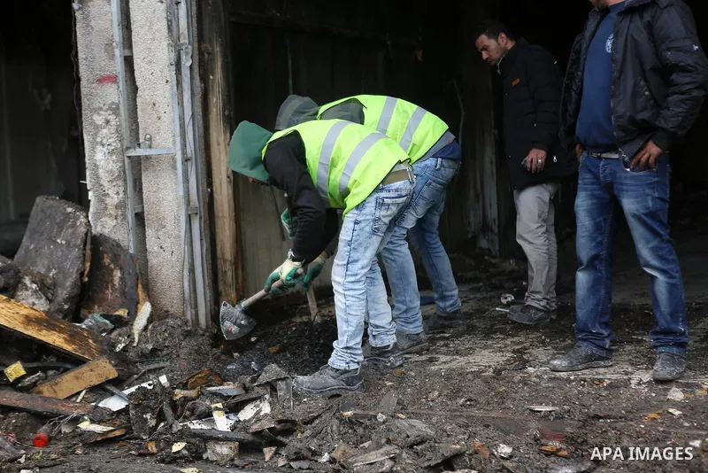 Palestinians check a money changer in the Palestinian political capital Ramallah after it was raided by Israeli forces, blowing up a safe and sparking a fire, on April 14, 2016. An Israeli army spokeswoman said the pre-d...