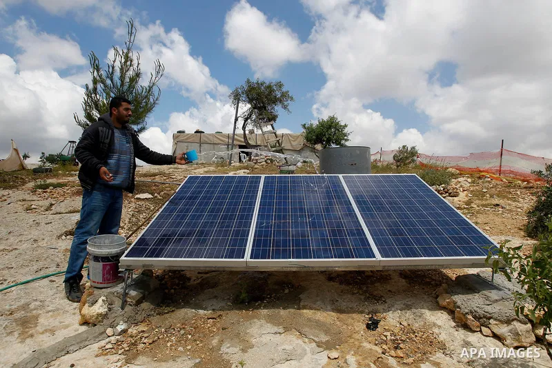 A Palestinian man of Hawamdeh family cleans solar panels outside a cave he lives in, in West Bank village of Mufagara, south of Hebron on April 14, 2016. Photo by Wisam Hashlamoun