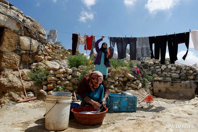 A Palestinian woman of Hawamdeh family washes dishes outside a cave she lives in, in West Bank village of Mufagara, south of Hebron on April 14, 2016. Photo by Wisam Hashlamoun