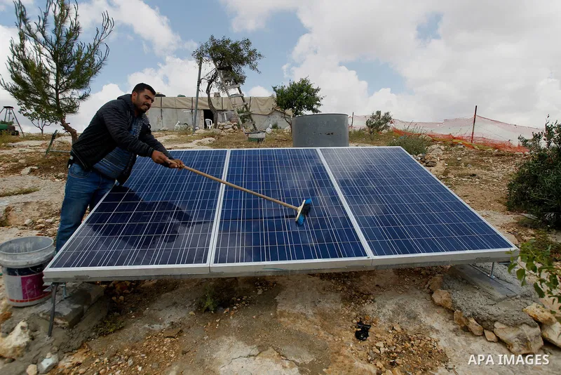 A Palestinian man of Hawamdeh family cleans solar panels outside a cave he lives in, in West Bank village of Mufagara, south of Hebron on April 14, 2016. Photo by Wisam Hashlamoun