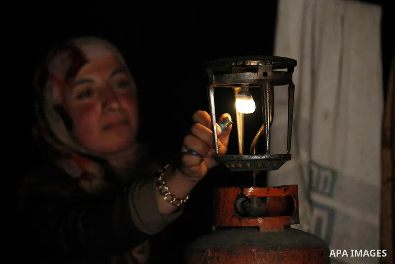 A Palestinian woman of Hawamdeh family lights a kerosene lamp inside a cave she lives in, in West Bank village of Mufagara, south of Hebron on April 14, 2016. Photo by Wisam Hashlamoun