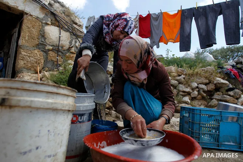 A Palestinian woman of Hawamdeh family washes dishes outside a cave she lives in, in West Bank village of Mufagara, south of Hebron on April 14, 2016. Photo by Wisam Hashlamoun