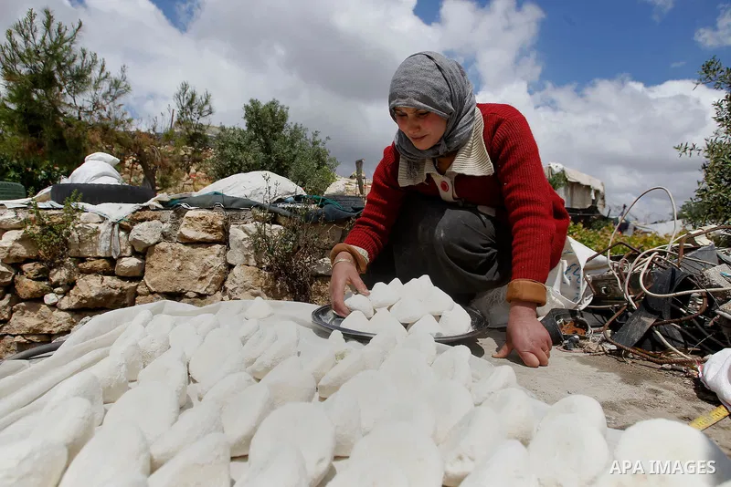 A Palestinian woman of Hawamdeh family cooks outside a cave she lives in, in West Bank village of Mufagara, south of Hebron on April 14, 2016. Photo by Wisam Hashlamoun