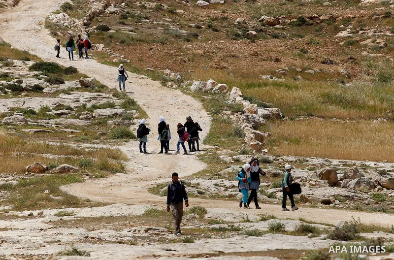 Palestinian students walk at street in West Bank village of Mufagara, south of Hebron on April 14, 2016. Photo by Wisam Hashlamoun