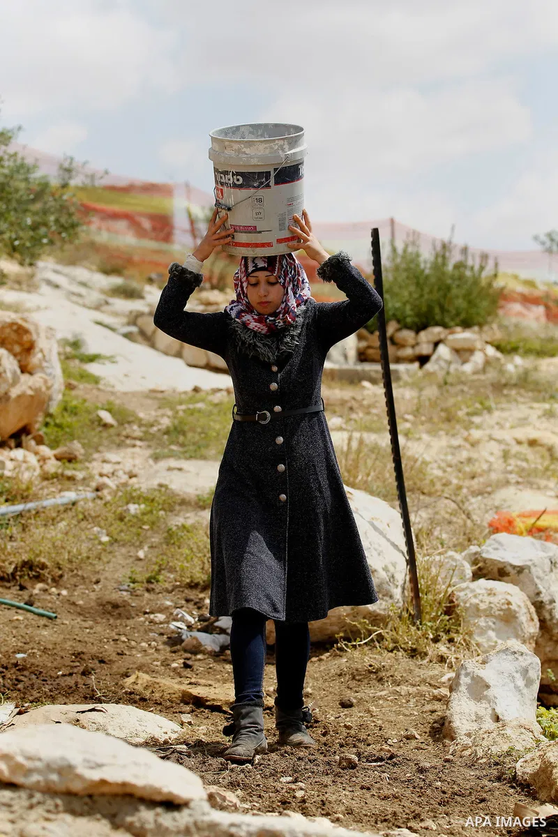 A Palestinian woman of Hawamdeh family takes water from a well outside a cave she lives in, in West Bank village of Mufagara, south of Hebron on April 14, 2016. Photo by Wisam Hashlamoun