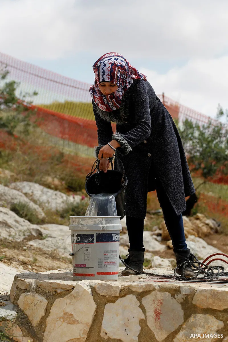 A Palestinian woman of Hawamdeh family takes water from a well outside a cave she lives in, in West Bank village of Mufagara, south of Hebron on April 14, 2016. Photo by Wisam Hashlamoun