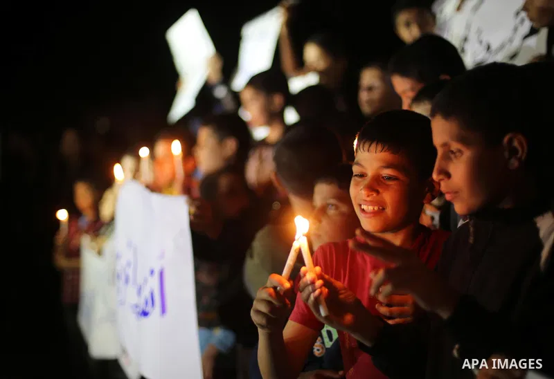 Palestinian children hold placards and light candles during a protest against a power cut in Gaza city on April 14, 2016. Photo by Mohammed Asad