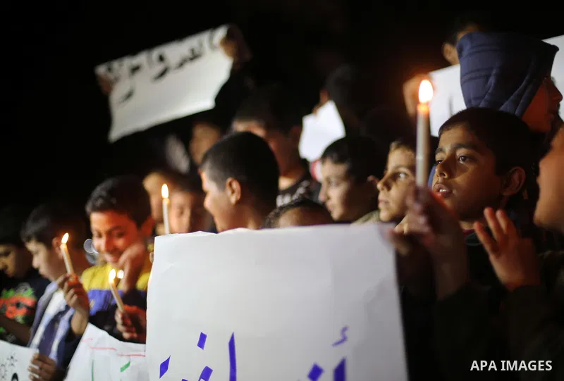 Palestinian children hold placards and light candles during a protest against a power cut in Gaza city on April 14, 2016. Photo by Mohammed Asad