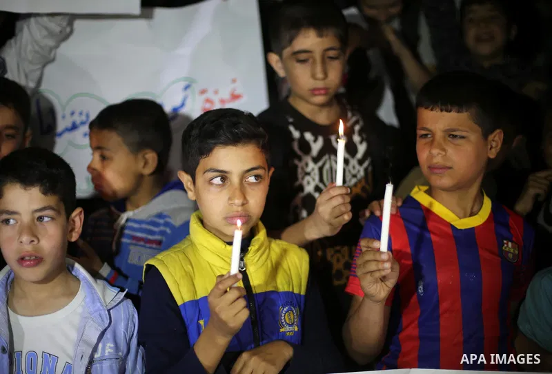 Palestinian children hold placards and light candles during a protest against a power cut in Gaza city on April 14, 2016. Photo by Mohammed Asad