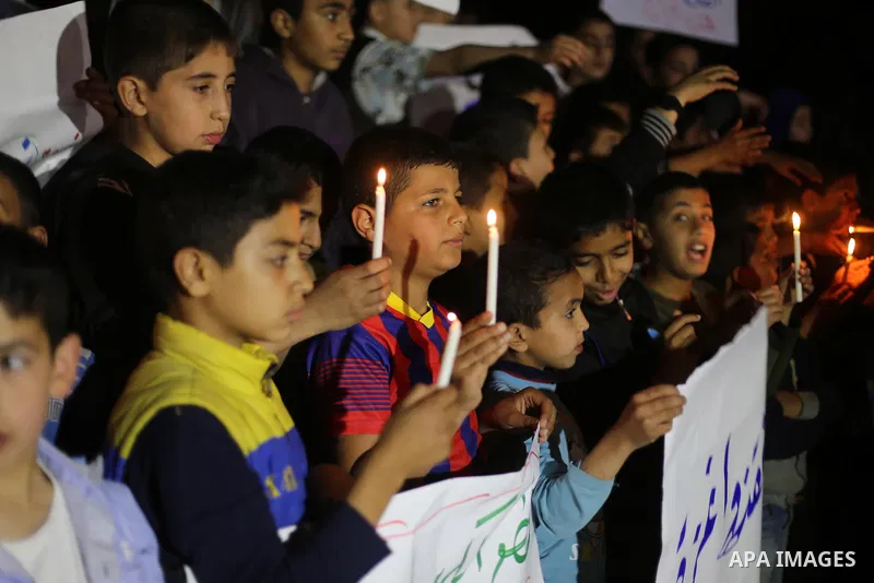 Palestinian children hold placards and light candles during a protest against a power cut in Gaza city on April 14, 2016. Photo by Mohammed Asad