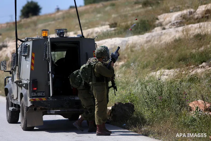 A member of Israeli security forces fires gas canisters during clashes with Palestinian protesters following a march against Palestinian land confiscation on April 15, 2016 in the West Bank village of Nabi Saleh near Ram...