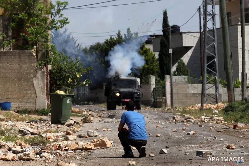 Palestinian protesters take cover from teargas fired by Israeli security forces during clashes following a weekly demonstration against the expropriation of Palestinian land by Israel in the village of Kfar Qaddum, near...