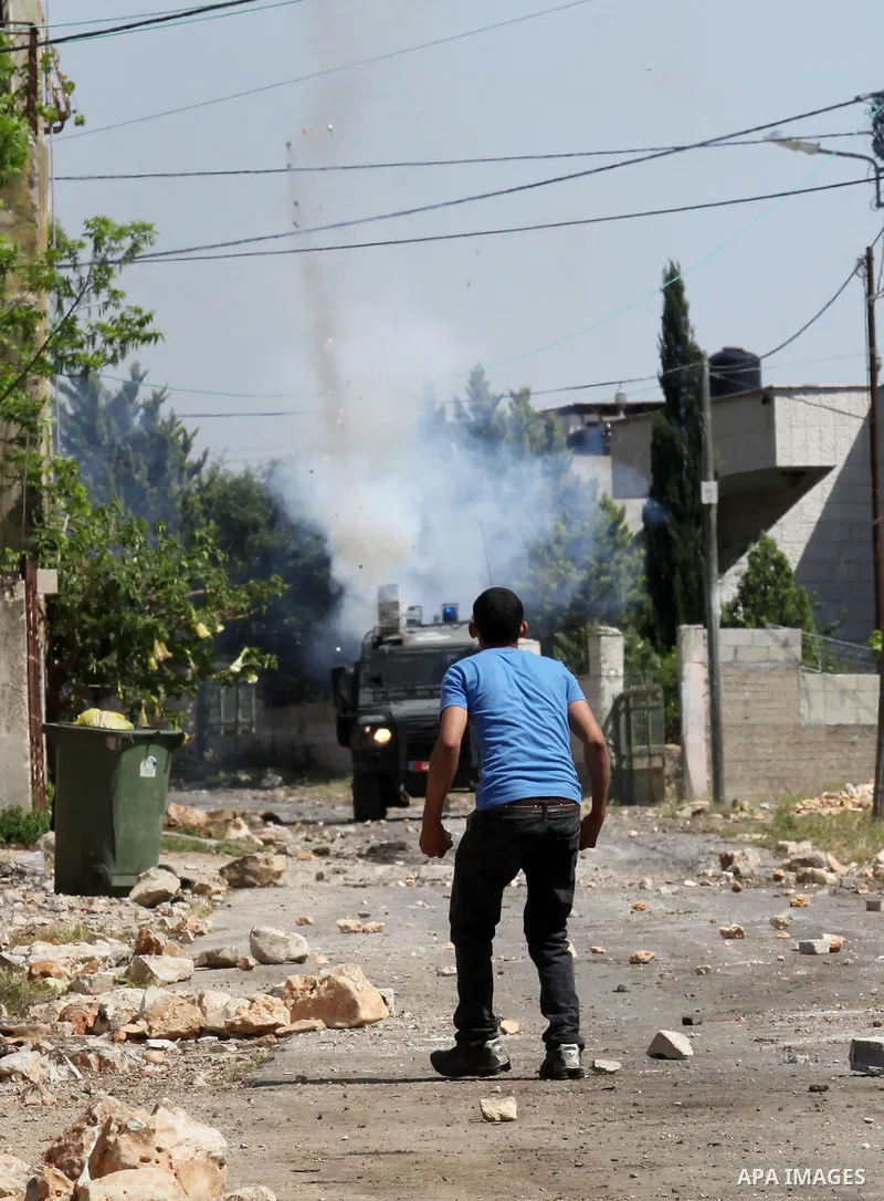 Palestinian protesters take cover from teargas fired by Israeli security forces during clashes following a weekly demonstration against the expropriation of Palestinian land by Israel in the village of Kfar Qaddum, near...