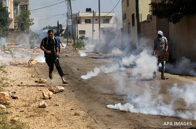 Palestinian protesters take cover from teargas fired by Israeli security forces during clashes following a weekly demonstration against the expropriation of Palestinian land by Israel in the village of Kfar Qaddum, near...