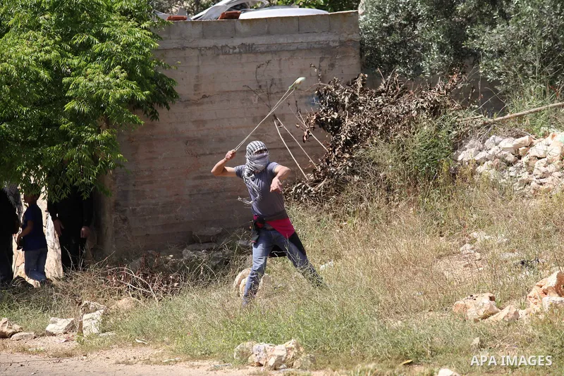 A Palestinian protester uses a slingshot to hurl stones towards Israeli security forces during clashes following a weekly demonstration against the expropriation of Palestinian land by Israel in the village of Kfar Qaddu...